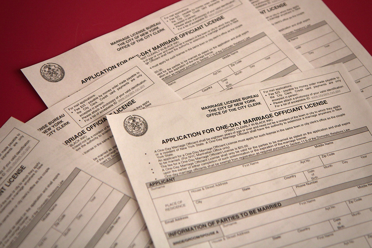 One-day officiant licenses application printouts cover an orange table.